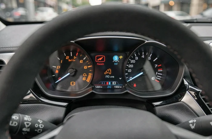 Gros plan sur le tableau de bord d'une Peugeot 208 avec voyants et symboles colorés allumés